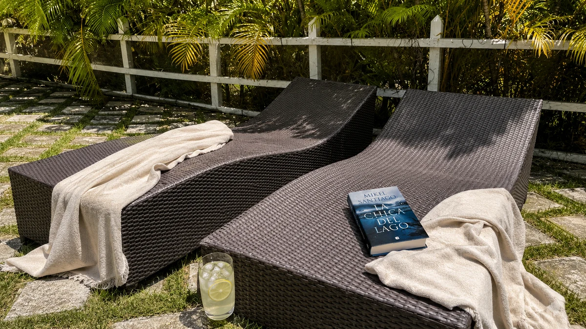 Libro La chica del lago sobre una hamaca junto a unas toallas y un refresco.