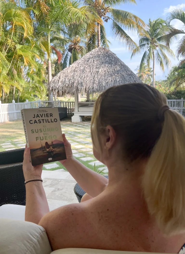 Leyendo "El susurro del fuego" de Javier Castillo en una terraza tropical de Punta Cana.